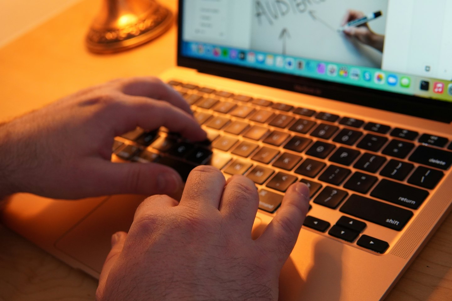 Person typing on a rose gold laptop keyboard.