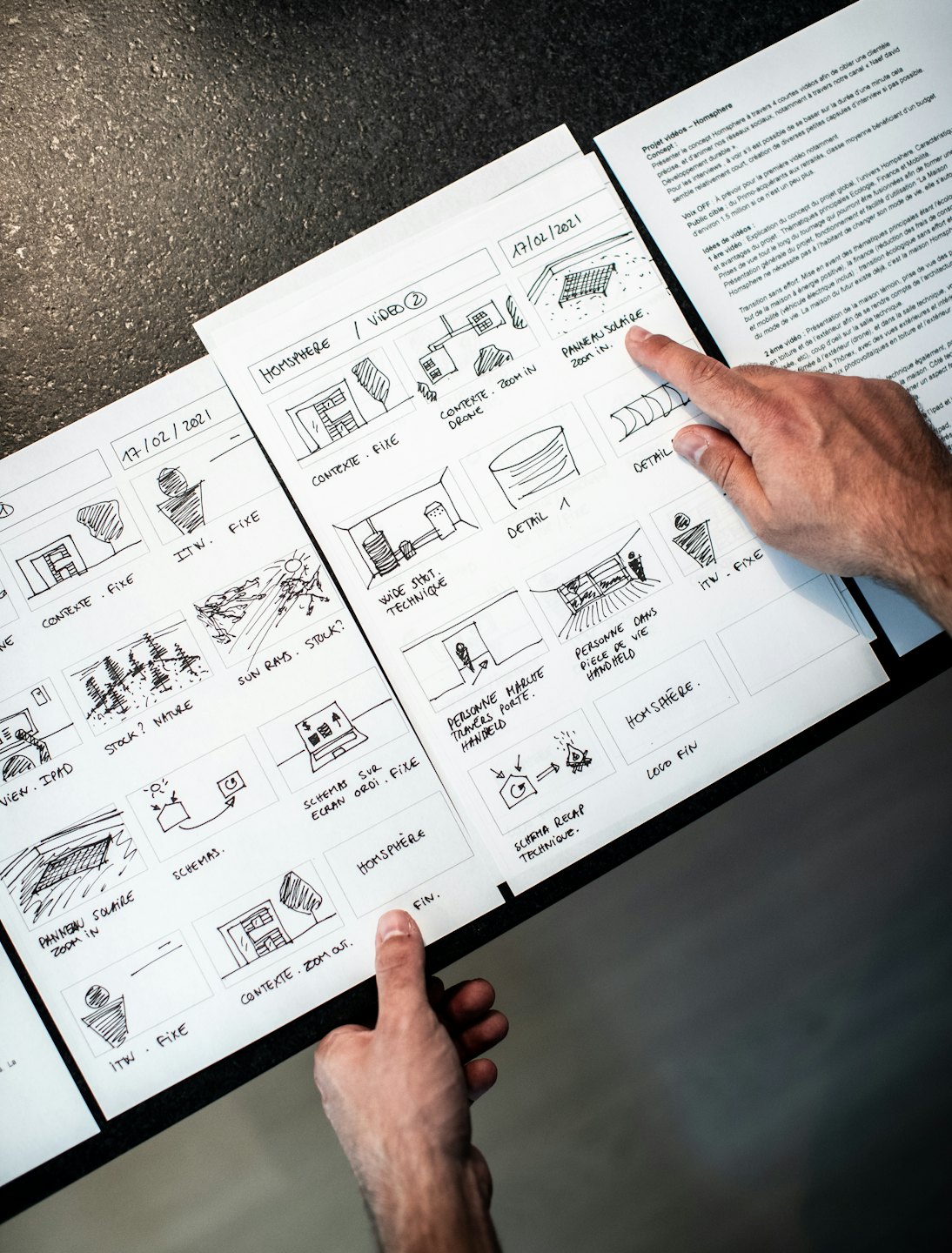 Hands pointing at a storyboard with sketches and French text.